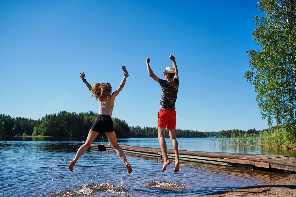 nuoret hyppää ilmaan rantavedessä